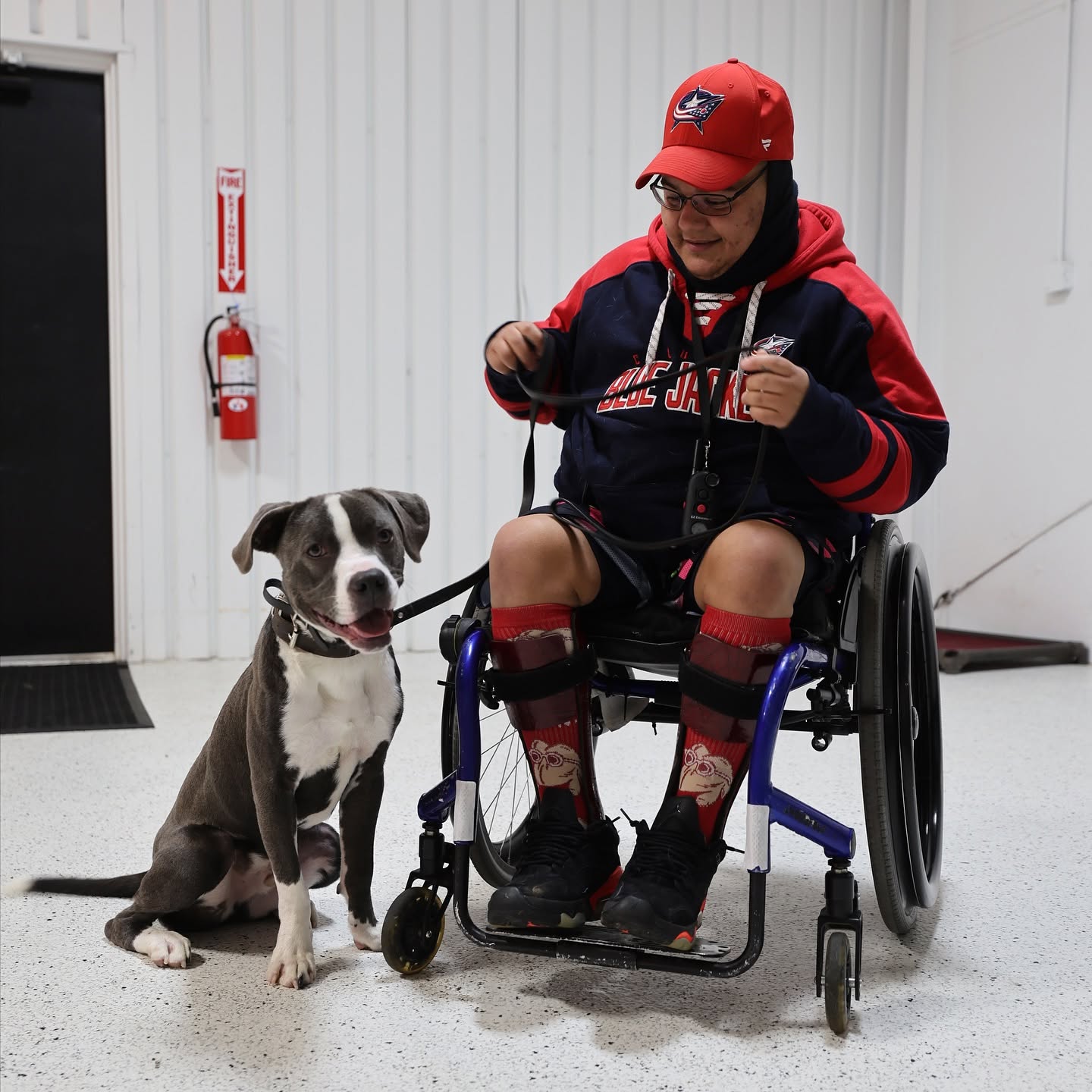 A young handler in a wheelchair holding the leash of their service dog